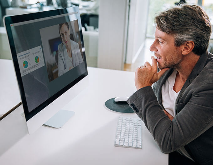 community treating oncology or hematology physician member of the Axess Network in front of a computer screen engaging in a virtual meeting program